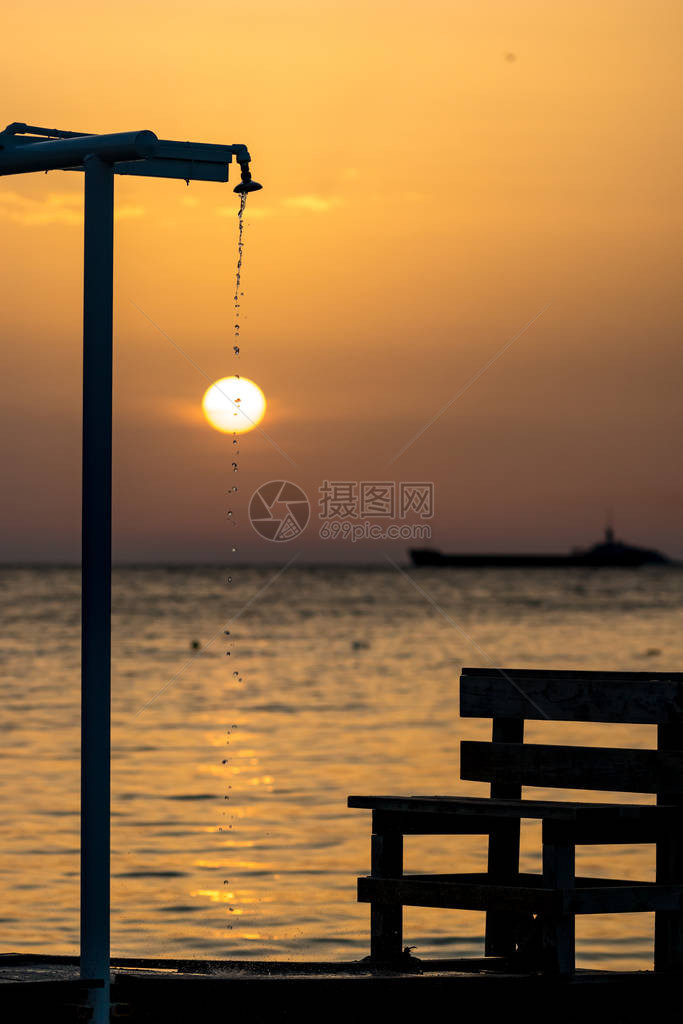 专注于淋浴时在海滩上滴水和长凳剪影图片