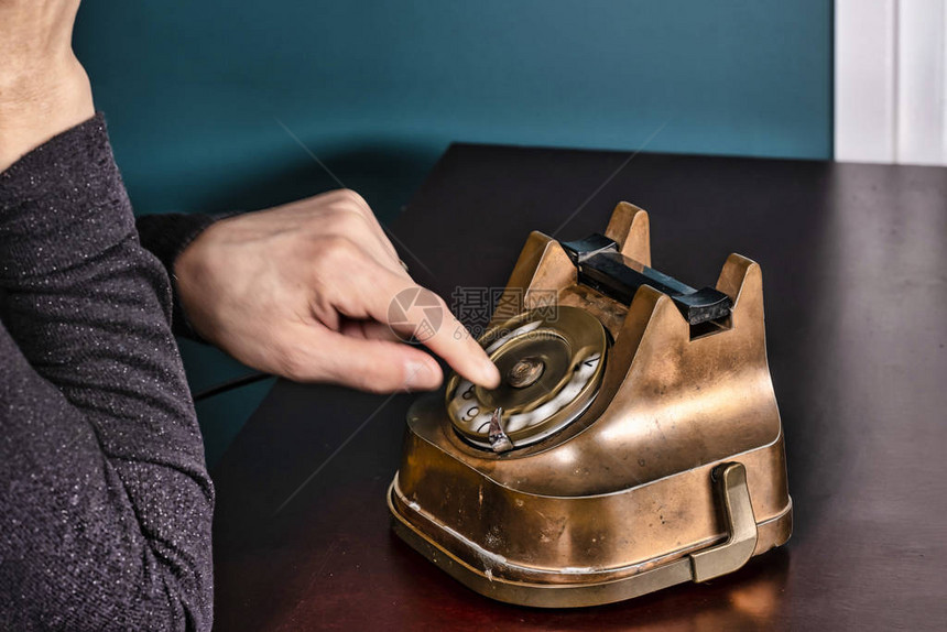 复古董经典过时的铜与大约1950年代的黑色旋转电话在木桌上图片
