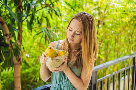 芒果放在女手中的可重复使用的袋子里图片