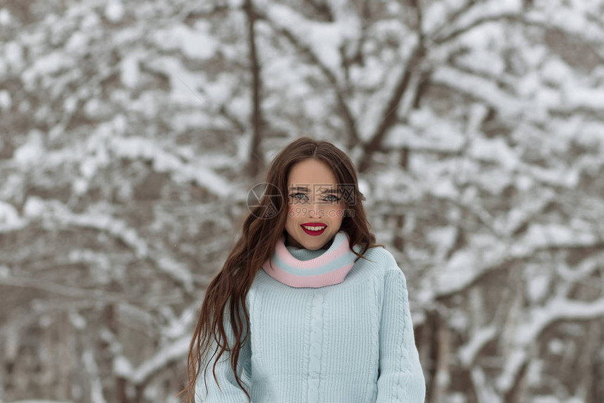 穿针织帽的年轻女调整温暖毛衣的脖子看着照相机在冬图片