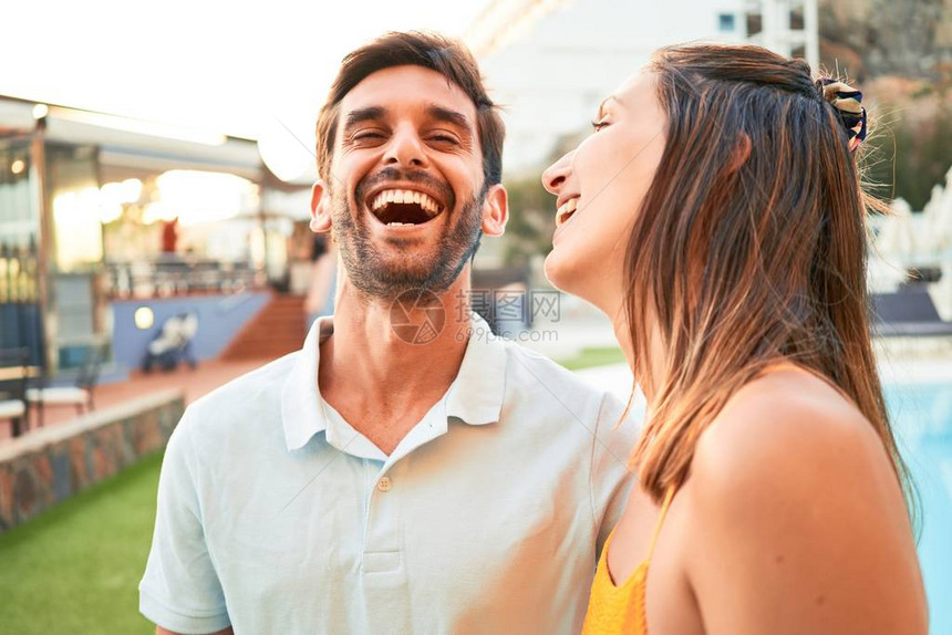 年轻漂亮的夫妇在度假时微笑着快乐和自信站在海滩俱图片