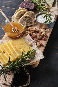 品尝不同类型的奶酪蜂蜜坚果香草夏巴塔面包和香肠木板上的几种奶酪浪漫图片