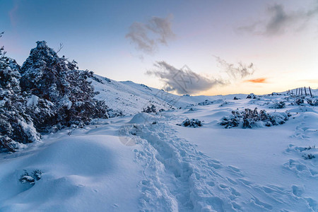 日落时栅栏附近的雪山路图片