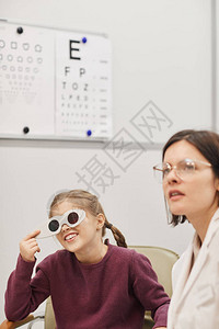 在复制空间的儿科眼诊所进行视力测试时阅读视觉图的可爱小女孩肖像图片