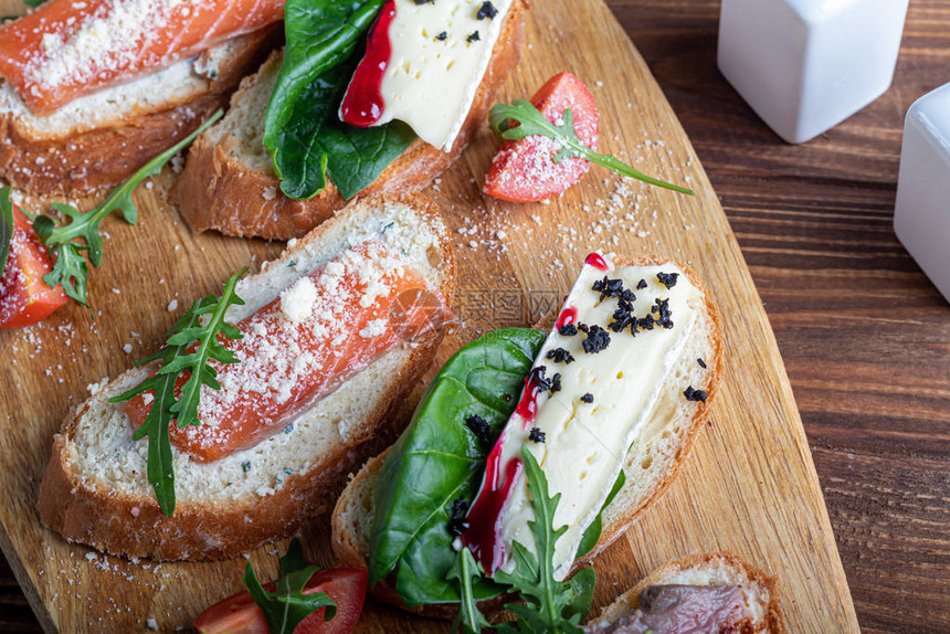 含红鱼的三明治苏维特牛肉和软奶酪涂满了微绿色青菜和番茄片在木质蛋白盘图片