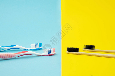 黄色和蓝色背景上的塑料和竹牙刷选择天然产品的概念拒绝塑料口腔护理图片