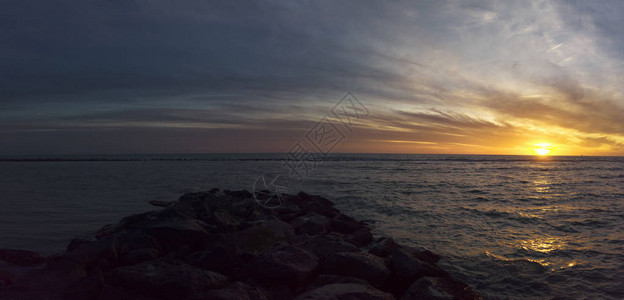 从岩石防波堤太阳升起的水面和风景优美的地平线图片