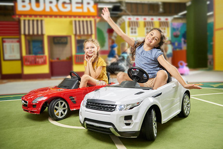 快乐的孩子们在室内游戏中心玩乐漂亮的女孩坐在游戏室的玩具车图片