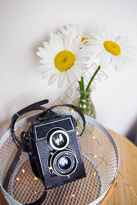 老式乡村相机木板上有一束雏菊花图片