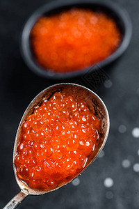 沙门红鱼子酱在一个精致的勺子中黑色背背景图片
