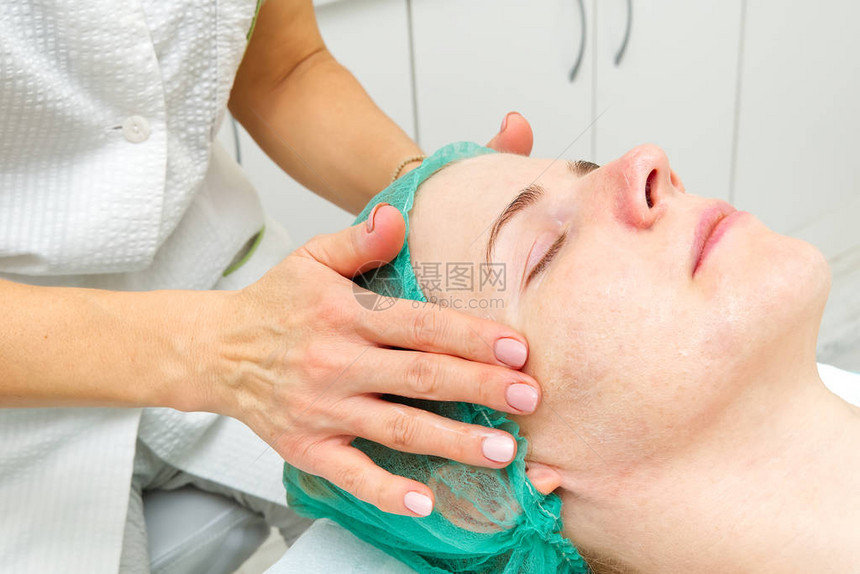 美容师将天然保湿面膜涂抹在年轻美女的脸上针对问题皮肤的抗衰老面膜和皱纹美容概念美图片