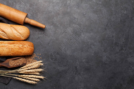 面粉和烹饪用具在石板上的各种小麦面包图片