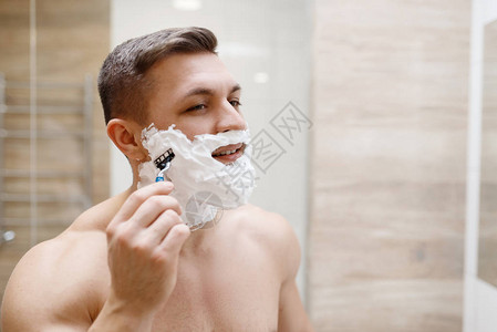 男子在洗手间用剃刀刮胡子图片