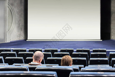 两个人在一间空旷的电影院里等待着不受欢迎的电影在白色屏幕背景图片