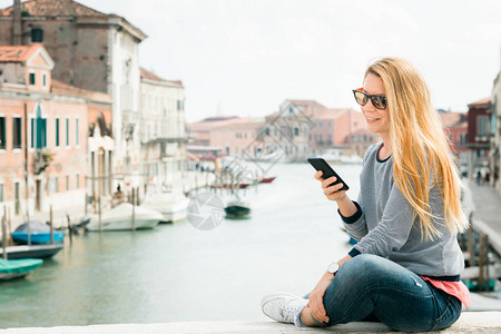 在意大利威尼斯穆拉诺岛桥上使用智能手机的年图片