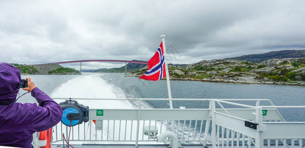 一艘渡轮旅行者拍摄了位于索格纳Fjord狭小地点的一座桥梁图片