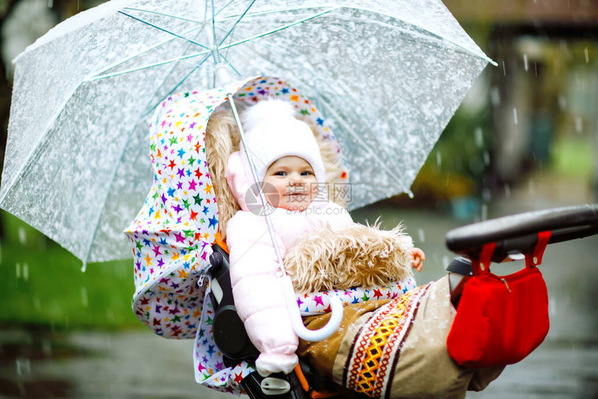 可爱的小漂亮女婴在寒冷的日子里坐在婴儿车或婴儿车里图片