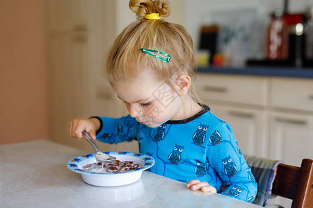 可爱的快乐宝贝孩子穿着五颜六色的衣服坐在厨房里图片