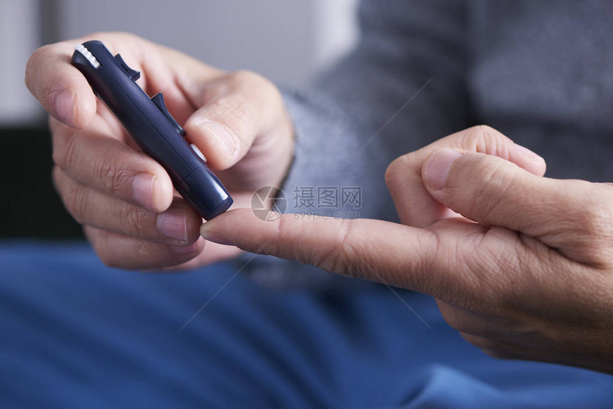 一个白人男子即将用指尖刺破手指来测量血糖仪中血图片