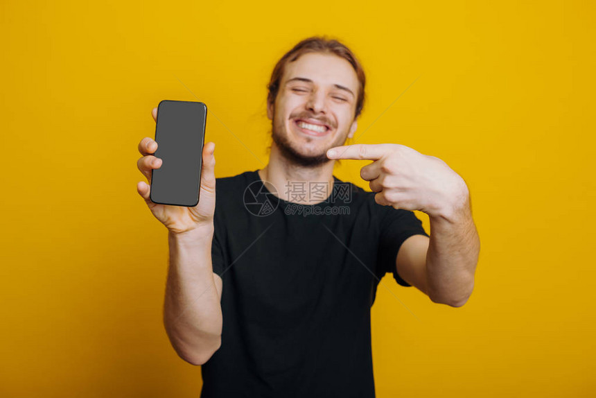 一个闭着眼睛笑着的男人指着他的电话广告在黄色背景上摆出某图片