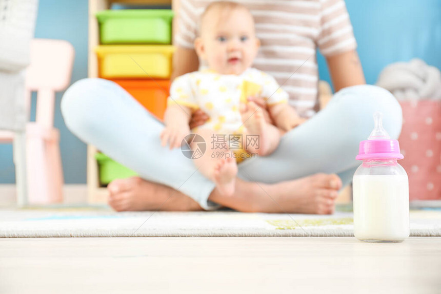 妈带着小婴儿和一瓶牛奶在地板上图片