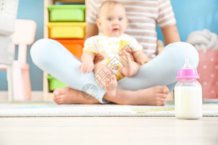 妈带着小婴儿和一瓶牛奶在地板上图片