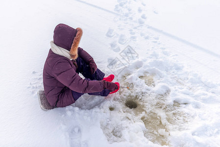 一个孤独的女孩垂钓者在进入暴风雪的白雪片中图片