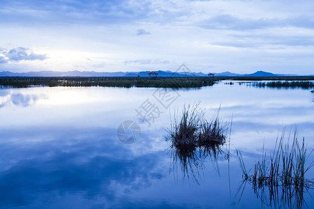 蓝色的云彩和落日的天空映照在热带湖面上图片