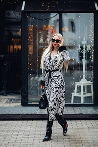 时尚的欧洲年轻女子戴着太阳镜在现代城市外部户外行走图片
