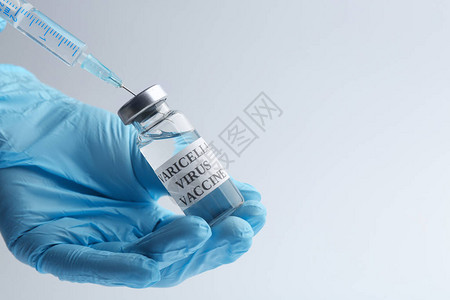 对医生在浅灰色背景空间上用天花疫苗填充注射器的仔细观察图片