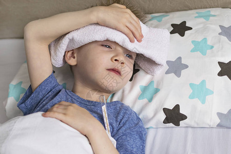 身处温度和头痛中的生病的悲伤儿童躺在床上图片