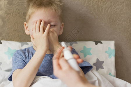 患有温度和头痛的生病的悲伤儿童躺在床上图片