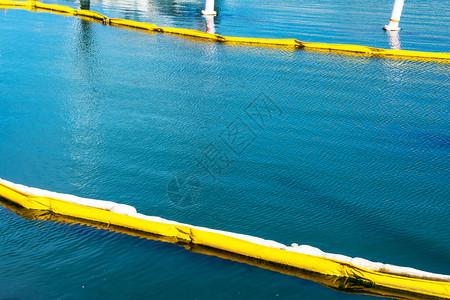 漂浮在平静水面上的黄色和白色油封围油栏污染概念围油栏是用于控制漏油的图片