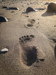 黄昏时海滩上黑沙滩上的男脚图片