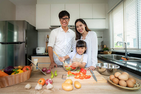 亚洲家庭与父亲母亲和女儿在家里厨房做饭时切碎蔬菜沙拉图片