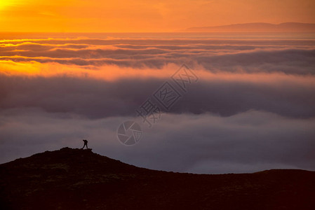 冰岛日落时在云海之上的山脊上的一图片