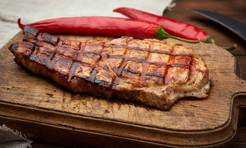 肋骨上的猪肉炒牛排躺在旧棕褐色木板上旁边图片