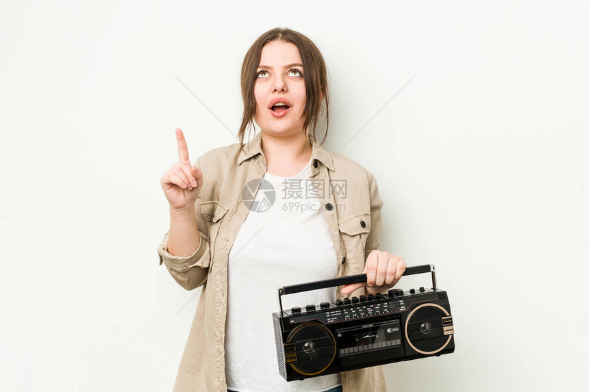 年轻的卷发女人拿着复古收音机用张开图片