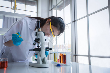 医学研究和科学家正在实验室中使用显微镜和平板电脑以及试管微量移液图片