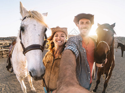 幸福的夫妇在马厩里与马自拍年轻农民在畜栏牧场与动物玩耍人与动物关系图片