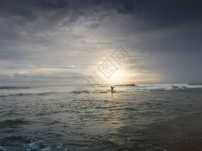男冲浪者在日落时寻找海图片