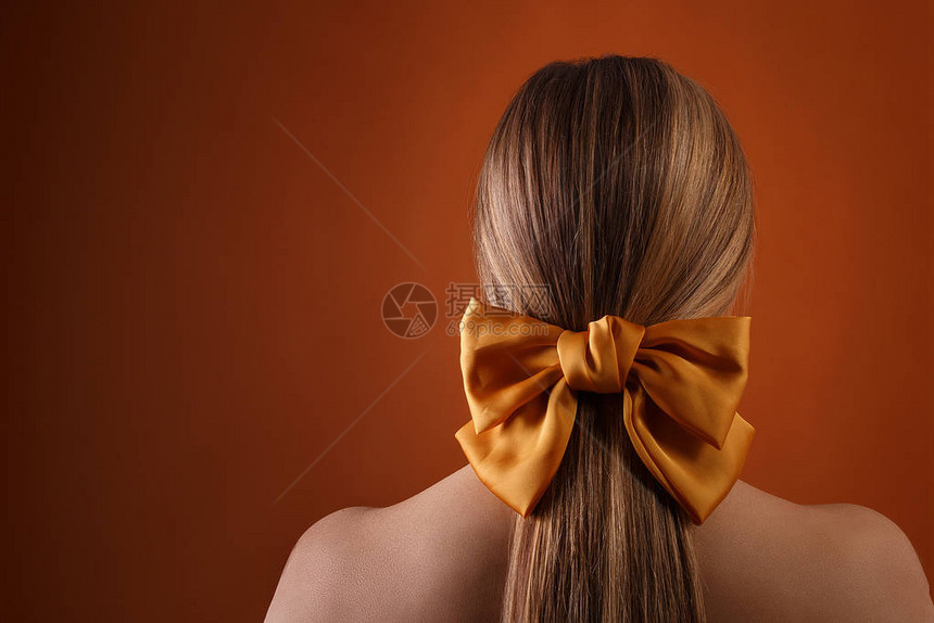 金发女发型与橙色墙背景与copyspace上的彩色丝带金发女孩头的特写图片