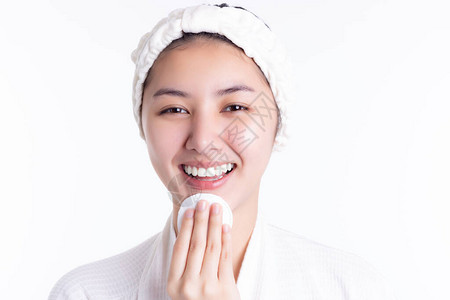 漂亮的亚洲女人通过擦拭使用化妆棉清洁乳液面部爽肤水来清洁美丽的脸庞图片