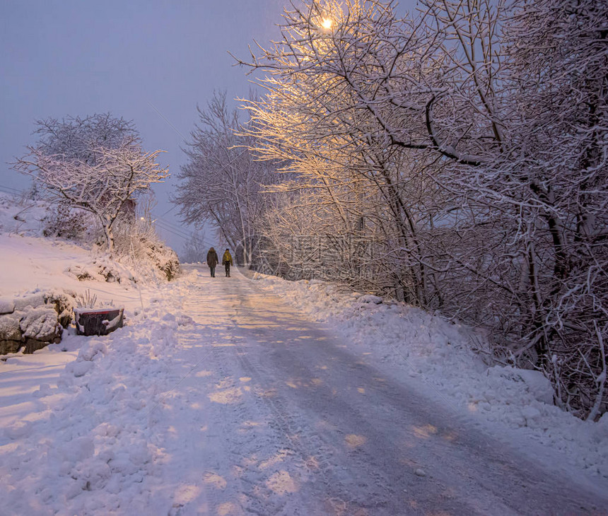 两个人在寒冷多雪的冬日走在路上图片