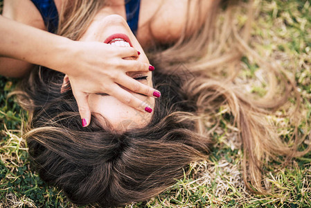 欢笑和快乐的人年轻女人躺在草地上并图片