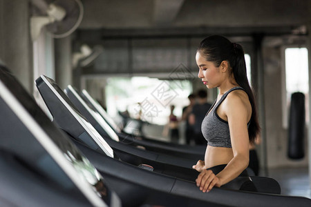 亚洲运动型女在跑步机上进行有氧运动以热身图片