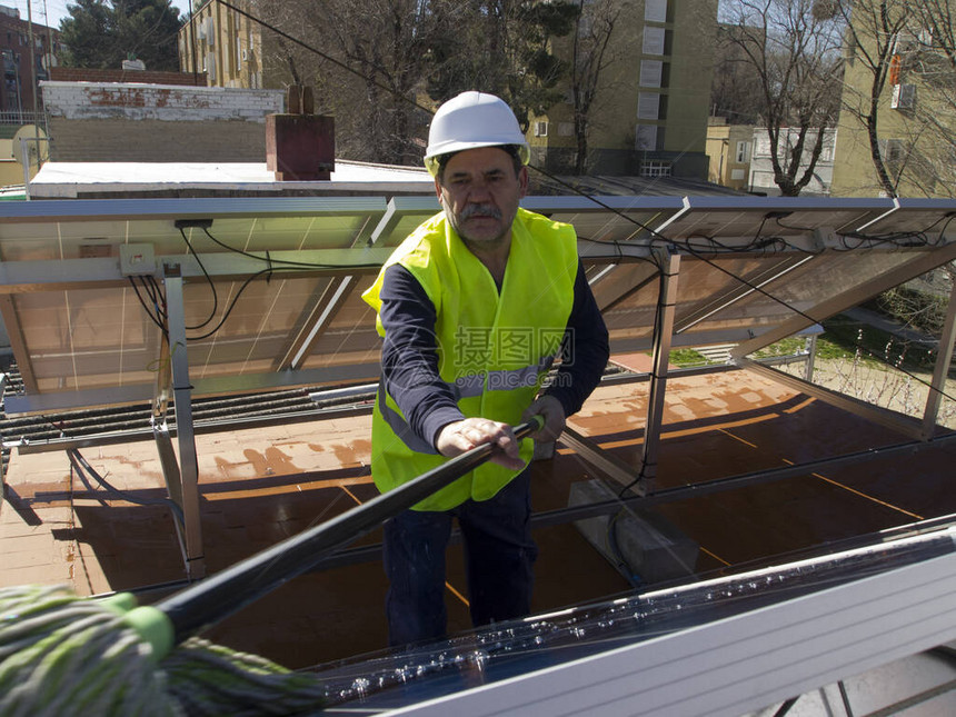 白种人经验丰富的技术人员用拖把清洁太阳能电池板图片
