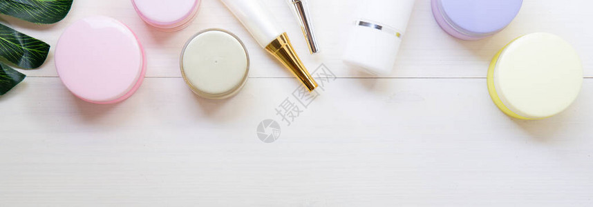 白木桌上的化妆品和护肤产品和绿叶图片