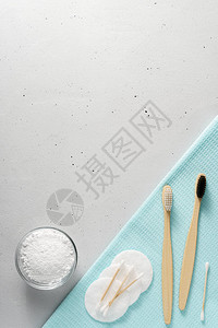 浅灰色混凝土背景上的两把竹牙刷洁牙粉棉垫和棍子顶视图图片
