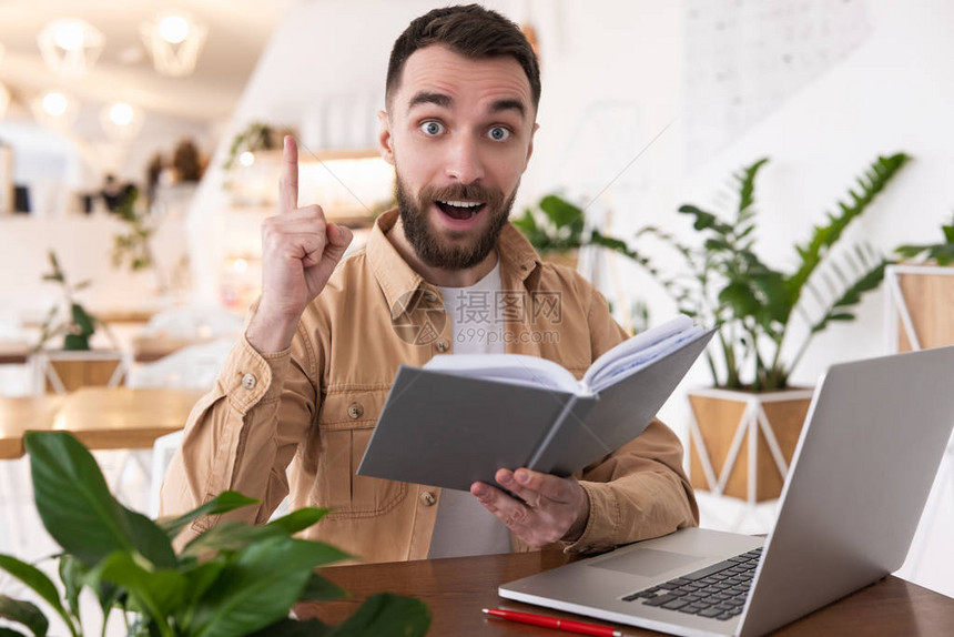 英俊的长胡子男在咖啡馆午餐休息时在看笔记本电脑的策划者的时候有个好主意图片